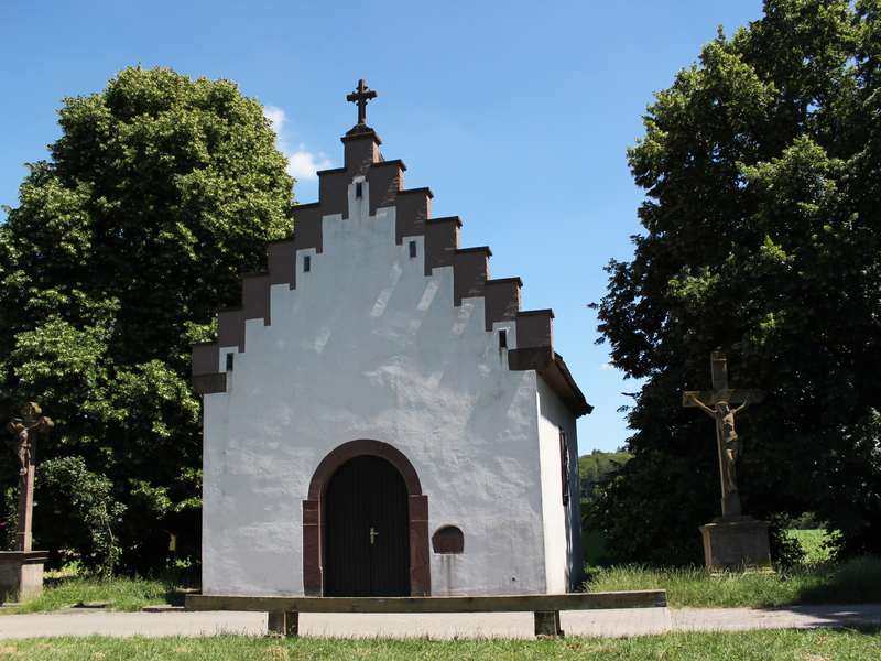 Kapelle zwischen zwei Bäumen unter blauem Himmel