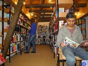 Junge liest ein Buch, Mann steht vor Bücherregal