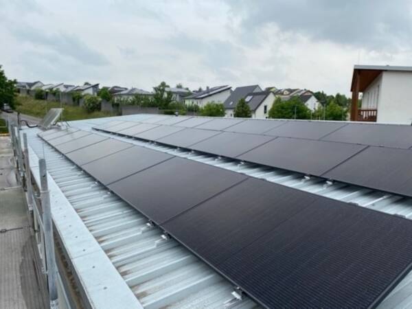 Photovoltaikanlage auf Metalldach mit Häusern im Hintergrund und grauem Himmel