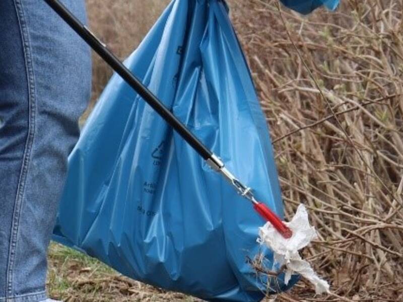 Müllsack und Greifer vor Busch