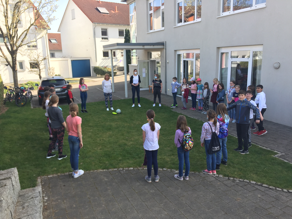 Kinder spielen auf einer Wiese im kreis mit einem Ball ein Spiel