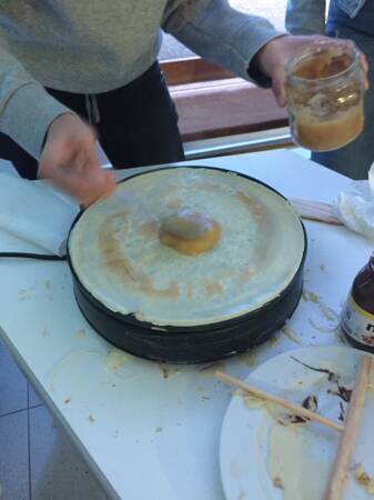 Ein Crêpe wird auf einem Crêpemaker mit Apfelmus bestrichen