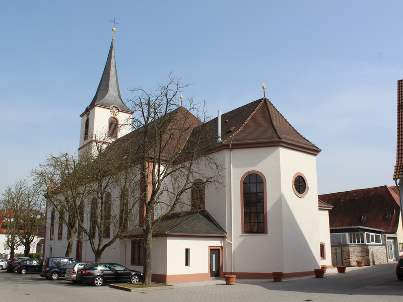 Große Kirche, die von dürren Bäumen abgedeckt wird und hellem blauen Himmel.