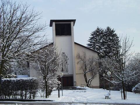 Frontalansicht moderne weiße Kirche im Schnee, Bäume rechts und links von der Kirche