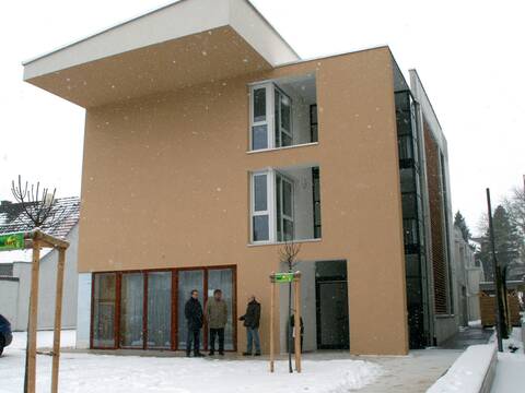 Ein großes Gebäude, Schnee fällt und liegt am Boden