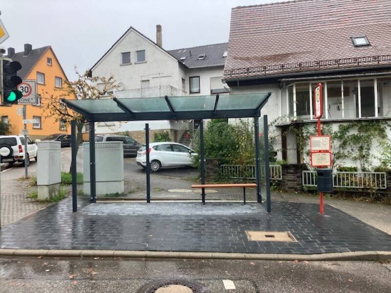 Neues Bushäuschen mit Glasdach auf grau gepflastertem Untergrund