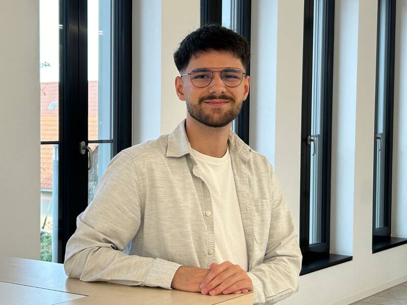 Portrait von Emre Kuz vor Fensterfront