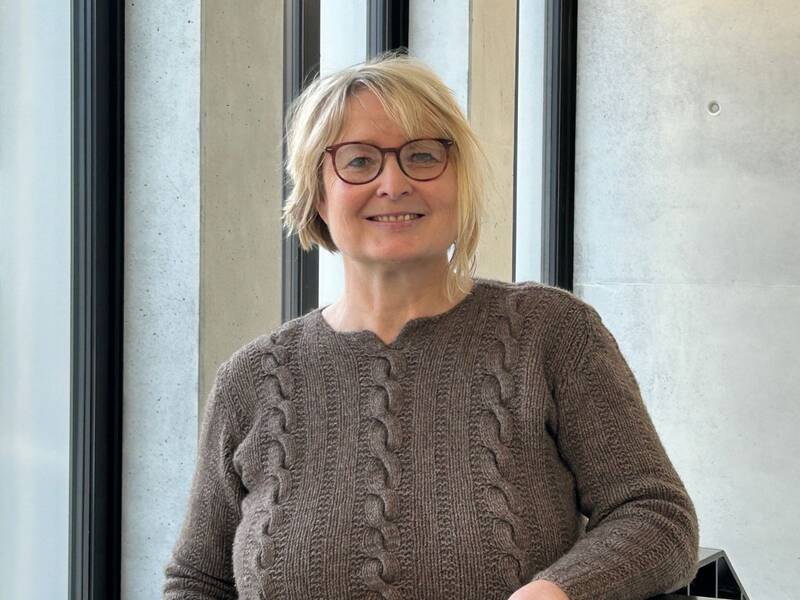 Portrait von Sandra Kämmer in beigefarbener Bluse vor Fensterfront