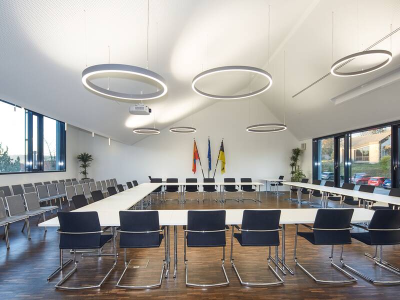 Ratssaal der Gemeinde Walzbachtal: dunkelbraunes Parkett, helle LED-Ring Lampen. links Besucherstühle, zentral  Sitzplätze von Rat und Verwaltung im Quadrat aufgestellt