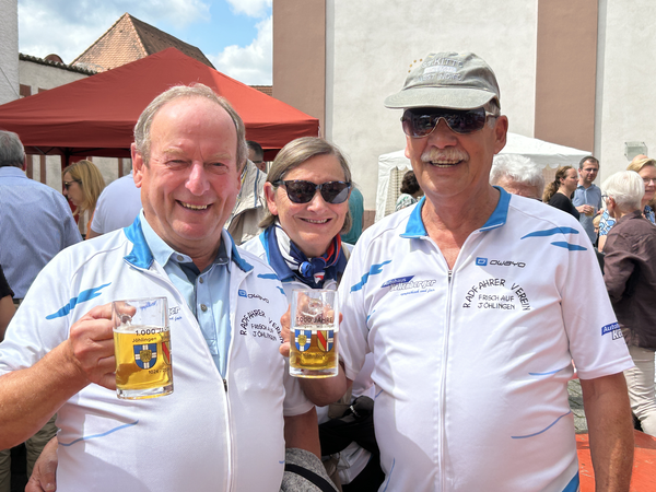 Drei Personen in weißen Fahrradtrikots mit Bierkrug