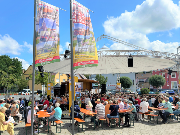 Menschenmassen auf Bierbänken mit Walzbachtaler Jubiläumsflaggen