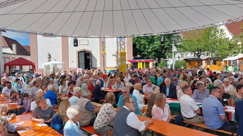 Menschenmassen vor der kath. Kirche beim Familienfest unter großem Schirm