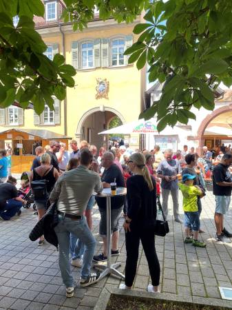 Besucher vom Familienfest auf dem Kirchplatz stehen an Stehtischen