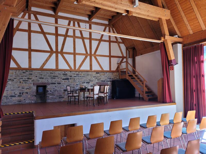 Bühne im Wössinger Hof. Trautisch und Stühle sind zu sehen. Im Hintergrund sieht man das Fachwerk des Gebäudes. Bestuhlung steht vor der Bühne.