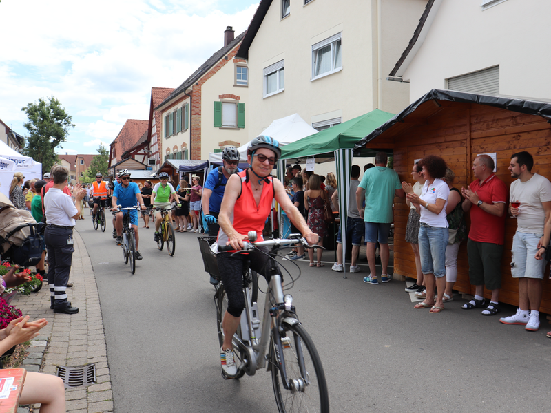 Fahrradfahrer die durch die Menge fahren. Rechts und links Zuschauer