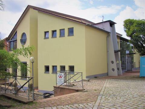 Schule Wössingen, gelbe Fassade, davor Pflastersteine