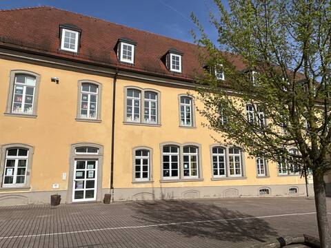 Kindertagesstätte Am Speyerer Hof im ehemalischen Schulhaus. Gelbe Fassade und viele bemalte Fenster