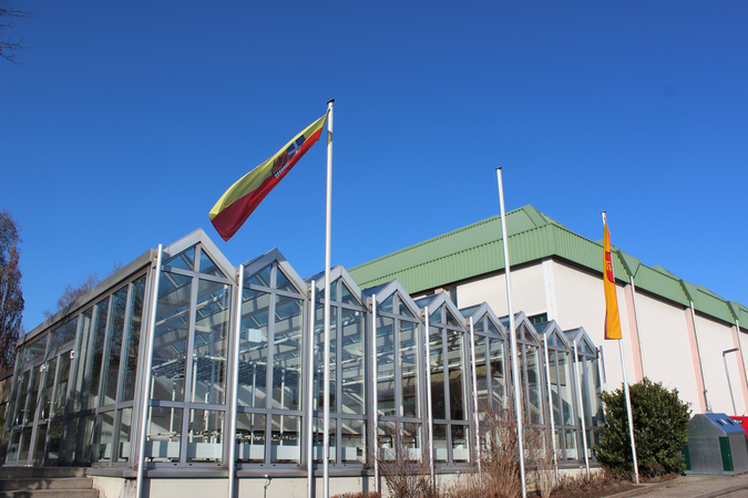 Sporthallengebäude mit Eingangsbereich aus Glas bei strahlend blauem Himmel