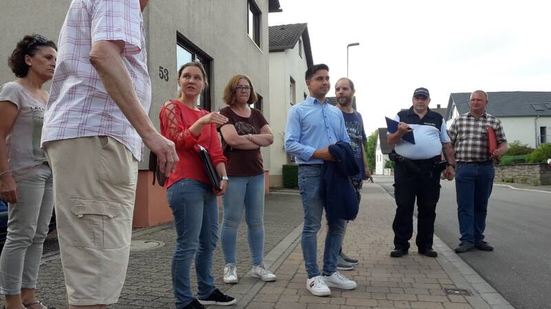 Herr Özcan und weitere Personen stehen auf einem Gehweg auf der Wössinger Straße