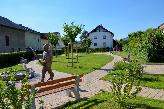 Bürgergarten in Wössingen. Darüber hinaus ist ein Haus im Hintergrund, der Mondspitzer und eine Bank zu sehen