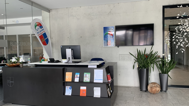 Infothek im Rathaus mit Broschüren und einer Flagge.