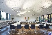 Hier ist der Ratssaal des Rathauses in Walzbachtal abgebildet. Dort gibt es für jeden Gemeinderat einen Tisch mit Stuhl sowie viele Besucherstühle