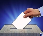 Männliche Hand wirft Wahlzettel in eine Wahlurne