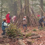 Eine Gruppe Kinder im Wald beim Höhle bauen.