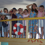 Kinder an einem Geländer mit einem Rettungsring schauen in die Ferne